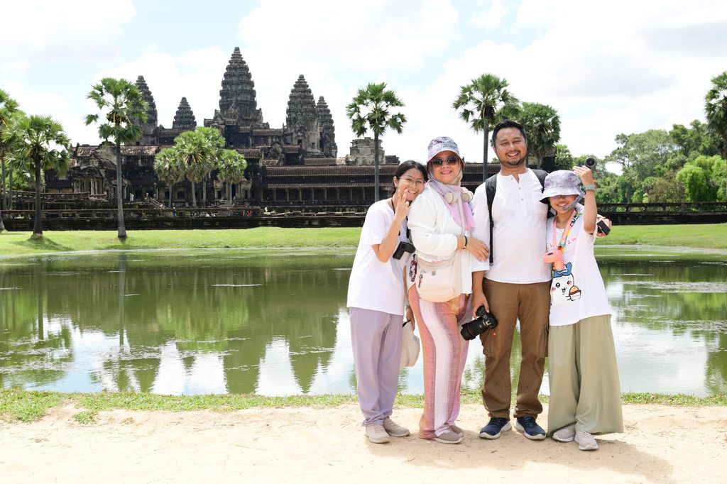The family by the reflecting pond with the towers of Angkor Wat behind them