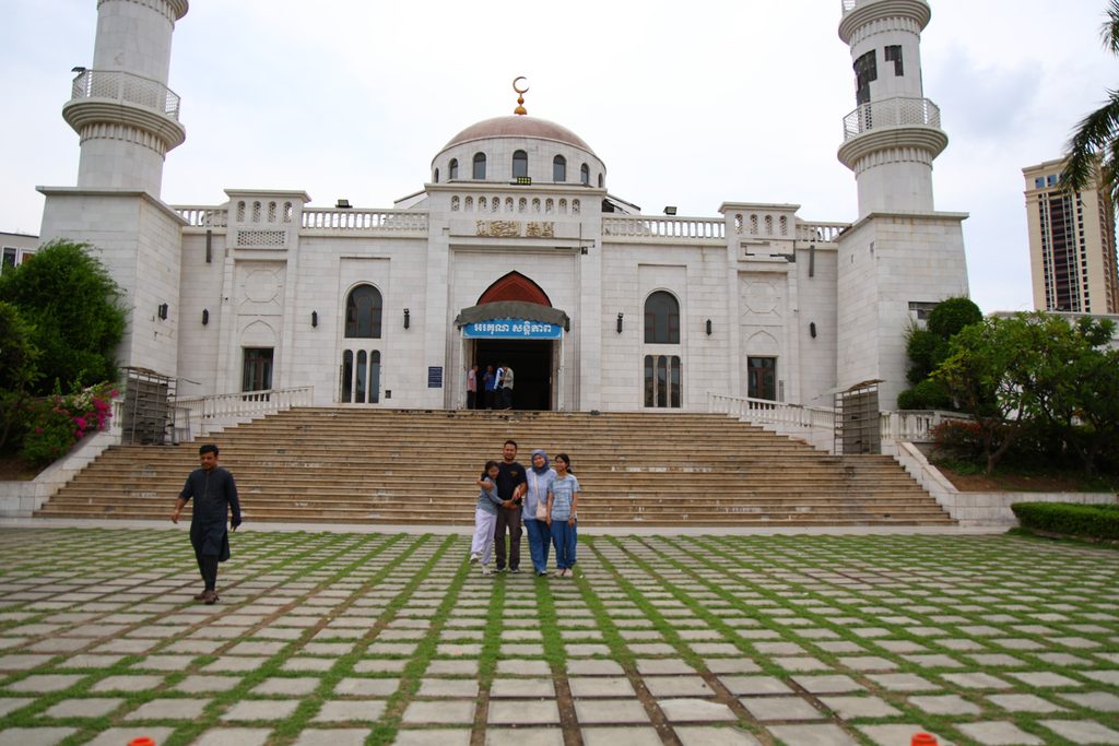 The family on the steps of Al Serkal Mosque, a white mosque with twin minarets in Phnom Penh