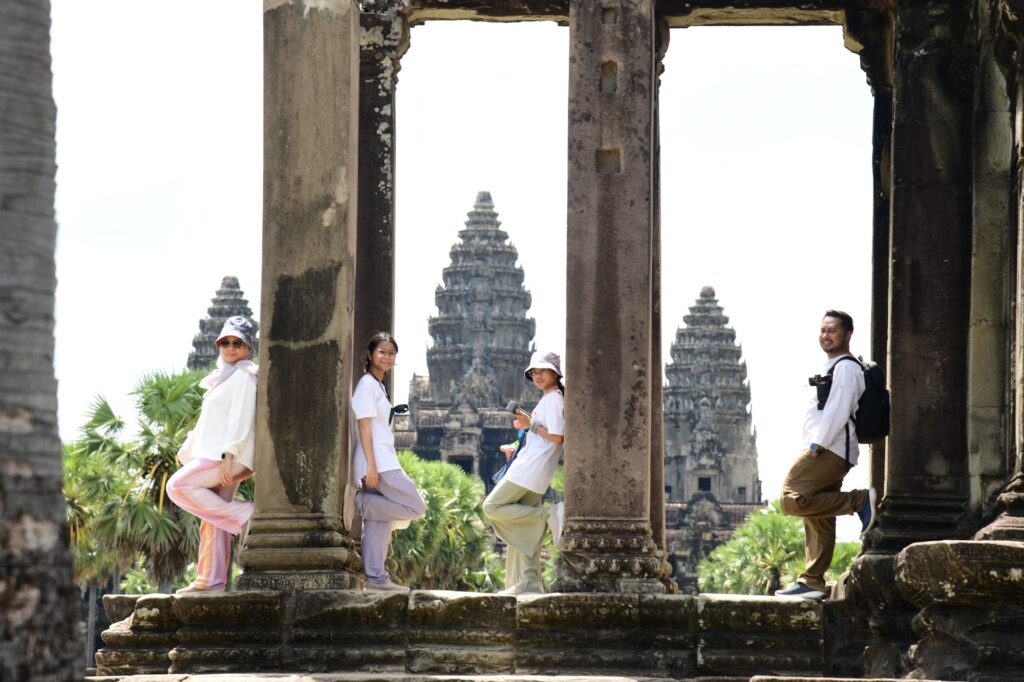The family posing between stone columns with Angkor Wat's central towers framed behind them