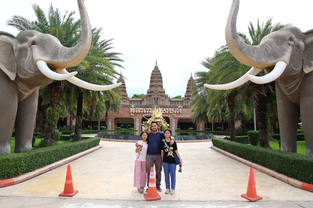 The family at the Phnom Penh Safari entrance, between two giant elephant statues